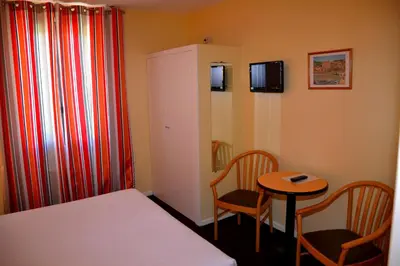 a small room with a bed and a table and chairs at Hotel Arc En Ciel in Èze