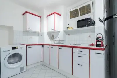 a black refrigerator in a kitchen with white cabinets at Prefecture Duplex - Old Town in Nice