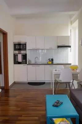 a kitchen with white cabinets and a table in a living room at Magnifiques Appartements au coeur du Vieux Nice in Nice