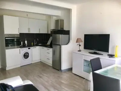 a kitchen with white cabinets and a tv on a counter at Charmant 2 pièces à 50 M de la mer in Cros-de-Cagnes