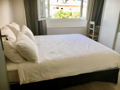 a white bed with white pillows and a window at Charmant 2 pièces à 50 M de la mer in Cros-de-Cagnes