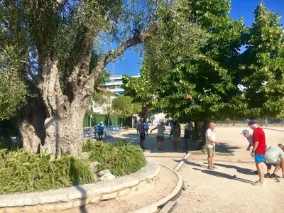 a group of people walking on a sidewalk next to a tree at Charmant 2 pièces à 50 M de la mer in Cros-de-Cagnes