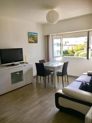 a living room with a table and chairs and a television at Charmant 2 pièces à 50 M de la mer in Cros-de-Cagnes