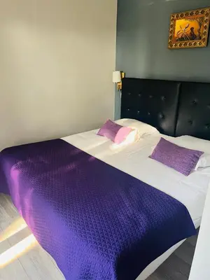 a large bed with purple sheets and pillows on it at Hôtel La Villa d'Eze in Èze