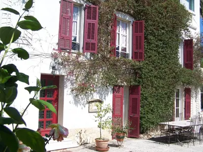 a building with red shutters and ivy at Castel Enchanté in Nice