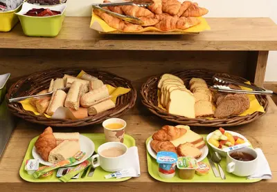 a table with baskets of bread and pastries and cups of coffee at ibis budget Nice Aeroport in Nice