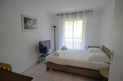 a white bedroom with a bed and a television at PLEIN CIEL - Appartement 5 personnes avec piscine sur la Corniche Fleurie à Nice in Nice