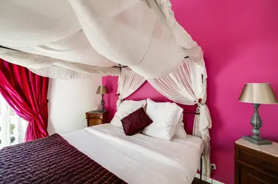 a bedroom with pink walls and a bed with a canopy at Villa Dracoena in Nice
