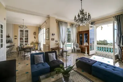 a living room with blue couches and a dining room at Villa Dracoena in Nice