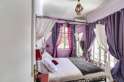 a bedroom with a canopy bed with purple curtains at Villa Dracoena in Nice