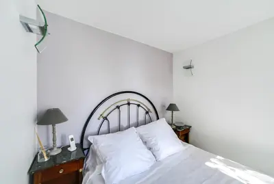 a bedroom with a bed with white sheets and two lamps at Villa Dracoena in Nice