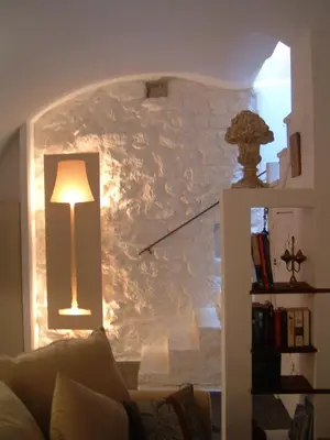 a living room with a lamp and a stone wall at La Suite du Village d'Eze in Èze