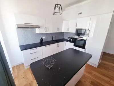 a kitchen with white cabinets and a black counter top at 
