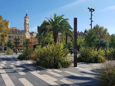 a courtyard with palm trees and a building with a clock tower at Residence Blue Harmony in Nice