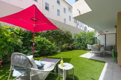 a patio with a red umbrella and a table and chairs at Residence Blue Harmony in Nice