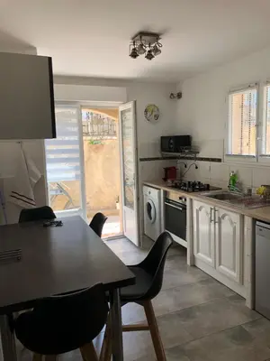 a kitchen with a table and chairs and an open door at appartement en rez de villa in Gattières