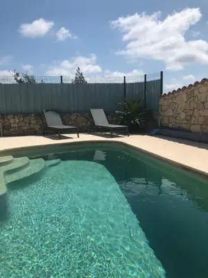 a swimming pool with two chairs next to a fence at appartement en rez de villa in Gattières