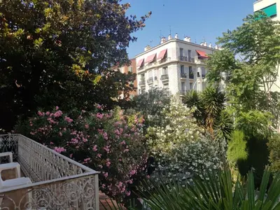 a garden with flowers and a building in the background at Hôtel Belle Meunière in Nice