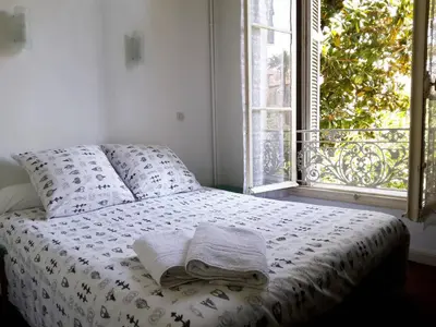 a bed with a white comforter and a window at Hôtel Belle Meunière in Nice