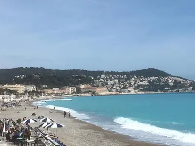 a beach with umbrellas and people on the beach at Promenade Gambetta in Nice
