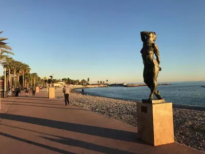 a statue of a woman standing next to a beach at Cros De Cagnes in Cagnes-sur-Mer