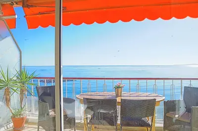 a table and chairs on a balcony with a view of the ocean at Cros De Cagnes in Cagnes-sur-Mer