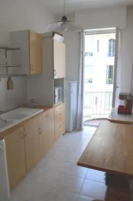 a kitchen with wooden cabinets and a large window at Le Catinat in Nice
