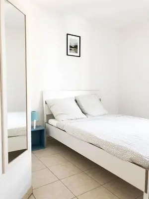 a white bedroom with a bed and a mirror at Arson Riquier Port in Nice