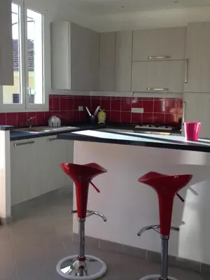 a kitchen with two red stools in front of a counter at Le 43 in La Trinité