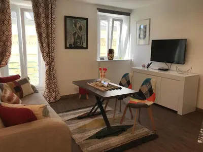 a living room with a table and a tv at Chouette Massena in Nice