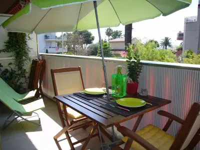 a table with two plates and an umbrella on a balcony at Le lutin in Saint-Laurent-du-Var