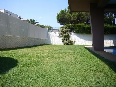a grassy yard with a fence and a retaining wall at Le lutin in Saint-Laurent-du-Var