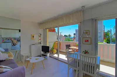 a living room with a couch and a table and a balcony at Le lutin in Saint-Laurent-du-Var