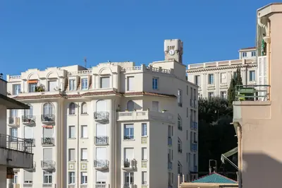 a white building with a clock tower on top of it at Suite Relax Five Stars Holiday House in Nice