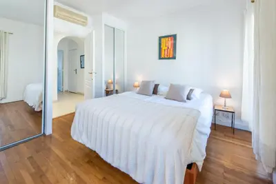 a white bedroom with a white bed and a mirror at The Queen in Nice