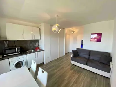 a living room with a couch and a kitchen at Studio, piscine in Saint-Laurent-du-Var