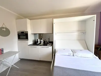 a small bedroom with a bed and a small kitchen at ApartHotel Riviera Nice Côte d'Azur - Old Town - Studio AC - Sea View - 50m Promenade des Anglais- LA MAISON LINDA in Nice