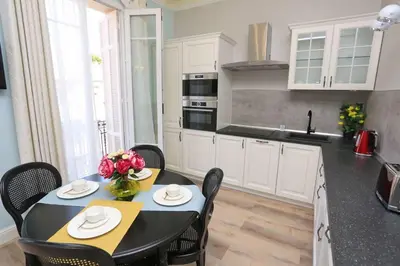 a kitchen with a table and chairs and a kitchen with white cabinets at Le Charme-35 in Nice