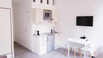 a white kitchen with a table and a microwave at Cosy central studio Nice Rossini large balcony in Nice