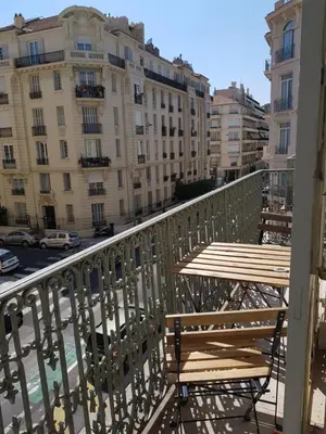 a balcony with two wooden tables and buildings at Cosy central studio Nice Rossini large balcony in Nice