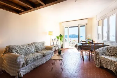a living room with two couches and a table and chairs at BELVEDERE AP1059 Villefranche-sur-Mer by Riviera Holiday Homes in Villefranche-sur-Mer