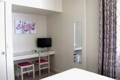 a bedroom with a desk with a television and two chairs at Hotel Le Havre Bleu in Beaulieu-sur-Mer