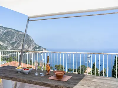a table on a balcony with a view of the ocean at Elegant Seaside Villa in Èze in Èze