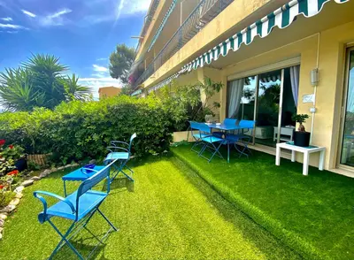 a patio with blue tables and chairs on the grass at Eden Barmassa in Villefranche-sur-Mer