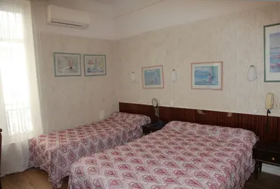 a hotel room with two beds and a window at Hotel Cronstadt in Nice