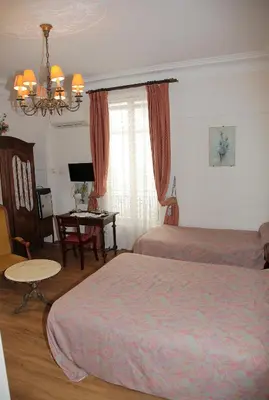 a hotel room with two beds and a table at Hotel Cronstadt in Nice