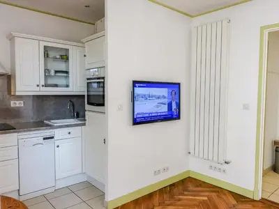 a kitchen with white cabinets and a tv on the wall at Apartment France by Interhome in Nice