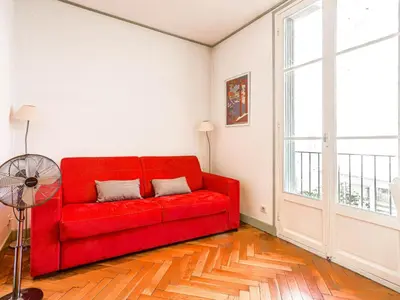 a red couch in a living room with a window at Apartment France by Interhome in Nice