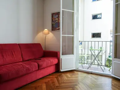 a living room with a red couch and a balcony at Apartment France by Interhome in Nice