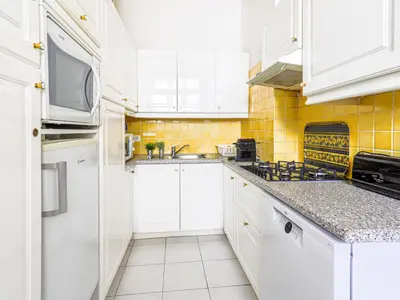 a kitchen with white cabinets and yellow tiles at Apartment La Floride Promenade des Anglais by Interhome in Nice